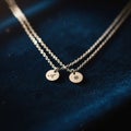 A Pair of Silver Necklaces with Initial Pendants on Dark Blue Velvet, Symbolizing Affection and Personal Connection Royalty Free Stock Photo