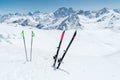 A pair of skis and ski poles stick out in the snow on the mountain slope of the Caucasus against the backdrop of the