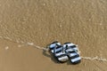 a pair of slippers in front of a beach with wave coming Royalty Free Stock Photo