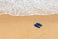 Pair of slippers in front of a beach with wave Royalty Free Stock Photo