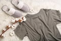 Pair of slippers, pajamas and cotton flowers on fuzzy carpet, flat lay. Comfortable home outfit