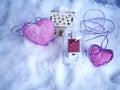 A pair of small toy houses with lighted illumination and a pair of pink hearts of felt on the snow