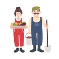 Pair of smiling male and female farm or garden workers carrying gathered harvest, shovel and bucket. Cute village couple Royalty Free Stock Photo