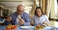 Pair of spouses are lunching in cafe, chatting, offering to each other to try meals Royalty Free Stock Photo