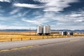 Pair of steel grain silos next to a divided highway along harvested fields Royalty Free Stock Photo