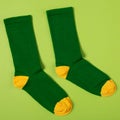 Pair of stylish green socks with yellow heels and toes, on green background, concept