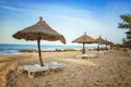 Pair of sunbed with parasol on beautiful empty beach near clear sea. It is a tropical paradise in Africa, Senegal. There is blue