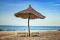 Pair of sunbed with parasol on beautiful empty beach near clear sea. It is a tropical paradise in Africa, Senegal. There is blue