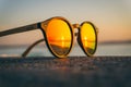 Pair of sunglasses on the beach with the reflection of the sunset Royalty Free Stock Photo