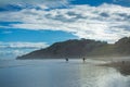 A pair of surfers walking into breaker water at Makorori Beach, mist rising over water obscuring distant mountains