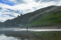 A pair of surfers walking over wet sand at Makorori Beach, mist rising over water obscuring distant mountains. Gisborne