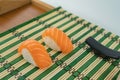 Pair of sushi with salmon sashimi on a green, beige bamboo mat Royalty Free Stock Photo