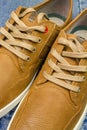 Pair of tan color, leather sneakers on jeans background, close-up view. Royalty Free Stock Photo