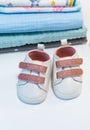 A pair of tiny sneakers for a newborn on a white background next to a stack of diapers Royalty Free Stock Photo