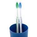 Pair of toothbrushes in blue plastic cup isolated over white background Royalty Free Stock Photo