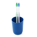 Pair of toothbrushes in blue plastic cup isolated over white background Royalty Free Stock Photo