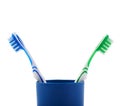 Pair of toothbrushes in blue plastic cup isolated over white background Royalty Free Stock Photo