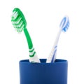 Pair of toothbrushes in blue plastic cup isolated over white background Royalty Free Stock Photo