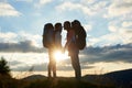 Couple of tourists in love with backpacks facing each other at sunset in the mountains Royalty Free Stock Photo