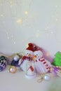 A pair of toy cheerful snowmen with a Christmas tree toy, decor on a light background with illumination