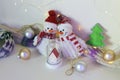 A pair of toy cheerful snowmen with a Christmas tree toy, decor on a light background with illumination