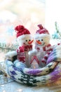 A pair of toy snowmen, a house, a scarf, Christmas decor, illuminations on a wooden surface on a window background Royalty Free Stock Photo