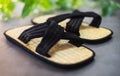 Pair of traditional Japanese bamboo zori shoes with decorative greenery in the background