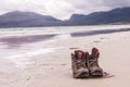 Pair of trekking boots on a remote beach with sea and mountains