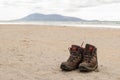 Pair of trekking boots on a remote beach with sea and mountains Royalty Free Stock Photo