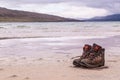 Pair of trekking boots on a remote beach with sea and mountains