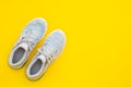 Pair of trendy sport sneakers on yellow background. Top view with copy space