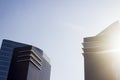 Pair of twins corporate black and blue buildings next to a gleaming sun.