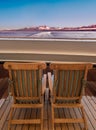 Two cruise ship wood lounge chairs facing sea and mountains at dawn, Alaska, USA Royalty Free Stock Photo