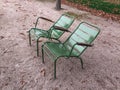 Pair of two empty garden chairs facing same directioin Paris park