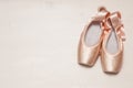 Pair of two satin russian pink ballet pointes lying on a white wooden background