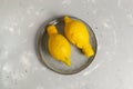 A pair of ugly lemons on a gray plate on a gray background.