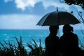 pair under an umbrella, ocean in the backdrop Royalty Free Stock Photo