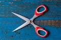 A pair of used children scissors against old blue wooden background