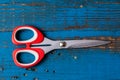 A pair of used children scissors against old blue wooden background