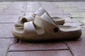 A pair of used clogs or sandals of synthetic material on a cobbled cement surface Royalty Free Stock Photo