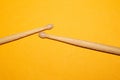 Pair of used drumsticks on yellow background