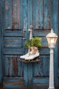 Pair of vintage white Ice Skates with Christmas decoration hanging on the blue rustic door and a big lantern Royalty Free Stock Photo