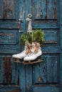 Pair of vintage white Ice Skates with Christmas decoration hanging on the blue rustic door Royalty Free Stock Photo