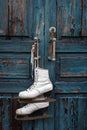 Pair of vintage white Ice Skates hanging on the blue rustic door Royalty Free Stock Photo