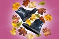 A pair of warm autumn black leather women`s boots on the pink background with bunch of autumn leaves