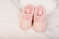 Pair of warm female slippers on white furry carpet