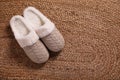 Pair of warm stylish slippers on wicker carpet, top view. Space for text