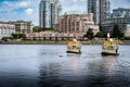 Pair of water taxi boats cross through the narrows of downtown harbour overlooking apartment buildings.