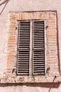 Pair of weatherd and deteriorating, green window shutters, on a1500\'s, crumbling building