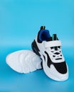 A pair of white and black sporty shoes for kid on blue background Royalty Free Stock Photo